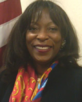Portrait of Denise Pease standing in front of American flag