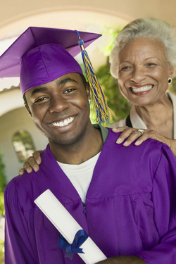 African American man in purple graduation gown with his mother behind him