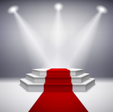 red carpet leading up steps to a stage with spotlights